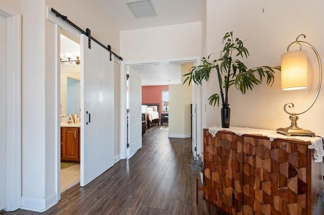 corridor with a barn door and dark wood-type flooring