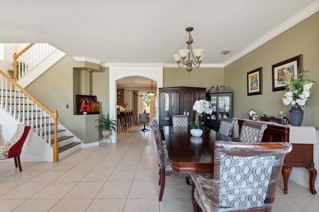 tiled dining area with crown molding and an inviting chandelier