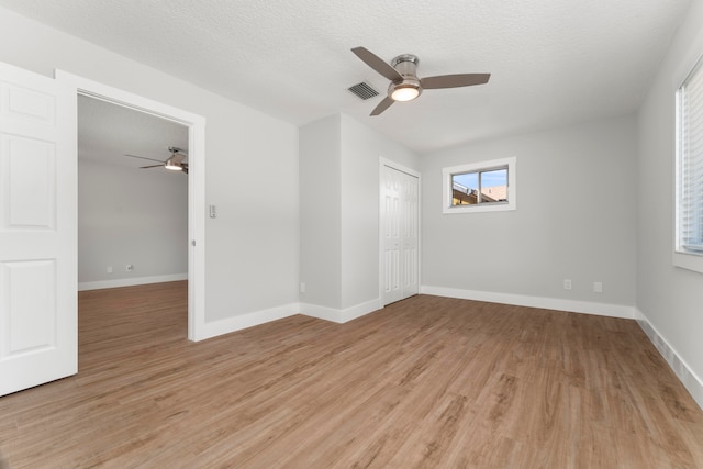 spare room with light hardwood / wood-style floors, ceiling fan, and a textured ceiling