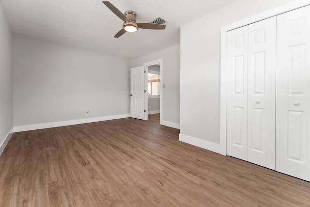 unfurnished bedroom featuring hardwood / wood-style flooring, a closet, ceiling fan, and a textured ceiling