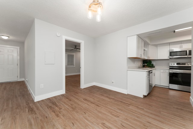 kitchen with ceiling fan, white cabinets, sink, stainless steel appliances, and hardwood / wood-style flooring