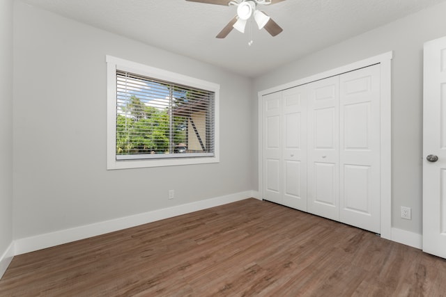 unfurnished bedroom with a textured ceiling, a closet, ceiling fan, and dark wood-type flooring