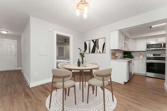 dining space with light hardwood / wood-style flooring, a textured ceiling, ceiling fan, and sink