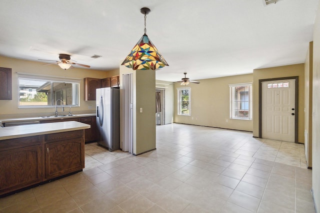 kitchen featuring a healthy amount of sunlight, sink, stainless steel fridge, and pendant lighting