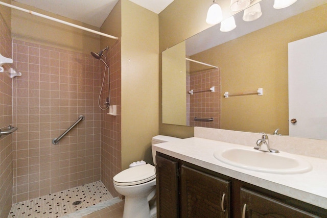 bathroom featuring a tile shower, tile flooring, toilet, and vanity with extensive cabinet space