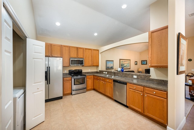 kitchen with appliances with stainless steel finishes, sink, washer / dryer, and light tile floors