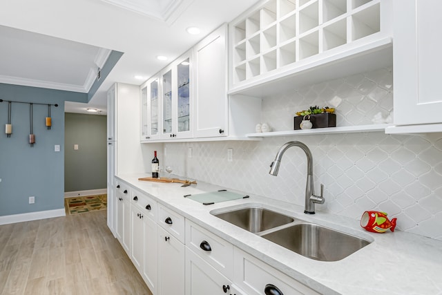 kitchen featuring backsplash, white cabinetry, sink, and light wood-type flooring