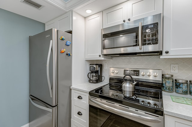 kitchen with appliances with stainless steel finishes, tasteful backsplash, white cabinets, and light stone counters