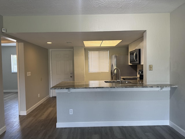 kitchen featuring kitchen peninsula, appliances with stainless steel finishes, and dark hardwood / wood-style floors