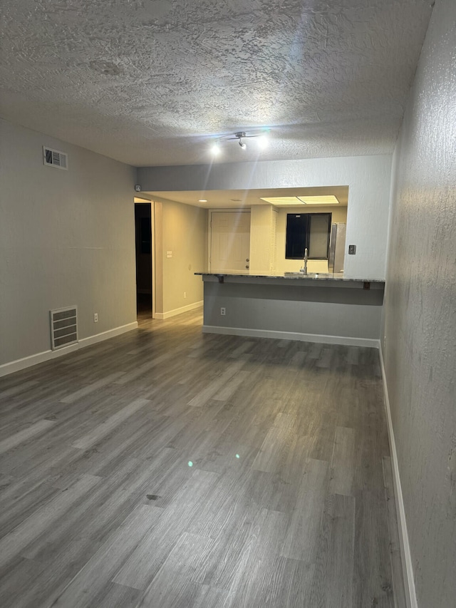 empty room featuring a textured ceiling, sink, and dark wood-type flooring