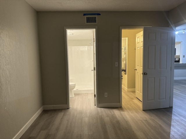 interior space featuring ensuite bath, a textured ceiling, and wood-type flooring