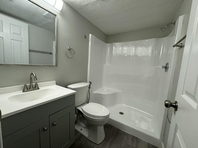 bathroom featuring walk in shower, large vanity, toilet, a textured ceiling, and hardwood / wood-style floors