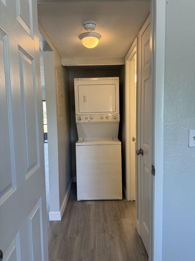 laundry room with dark hardwood / wood-style flooring and stacked washer and clothes dryer