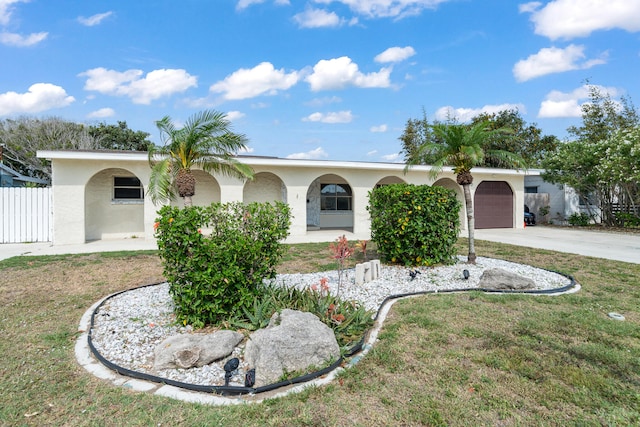 ranch-style home with an attached garage, covered porch, fence, driveway, and stucco siding