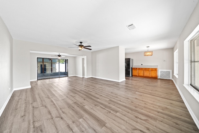 unfurnished living room with ceiling fan with notable chandelier and hardwood / wood-style floors