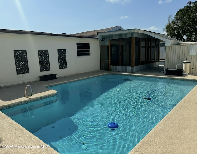 outdoor pool featuring a sunroom and a patio