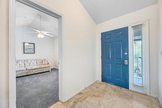 carpeted foyer entrance featuring vaulted ceiling, ceiling fan, and a textured ceiling