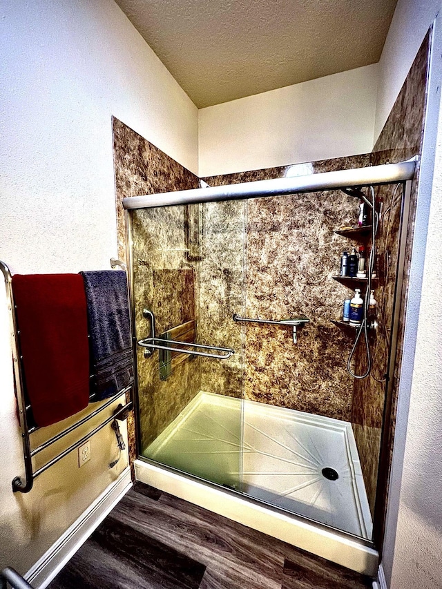 bathroom featuring wood-type flooring, a textured ceiling, and an enclosed shower