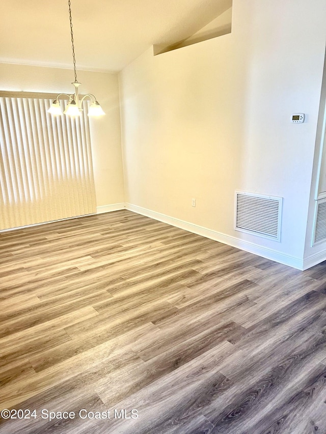 unfurnished dining area featuring a chandelier, wood-type flooring, and vaulted ceiling