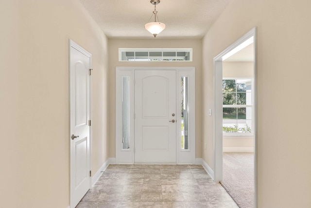 foyer entrance with light colored carpet and a textured ceiling