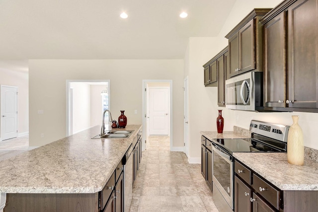 kitchen with dark brown cabinets, sink, stainless steel appliances, and an island with sink