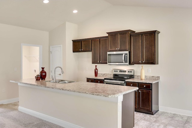 kitchen featuring an island with sink, stainless steel appliances, dark brown cabinets, vaulted ceiling, and sink