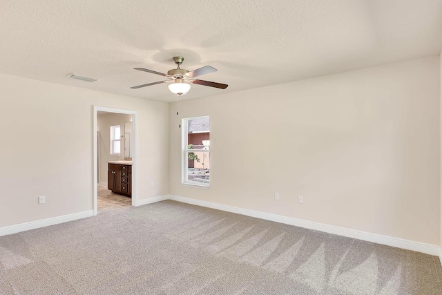 unfurnished room with ceiling fan, light colored carpet, and a textured ceiling