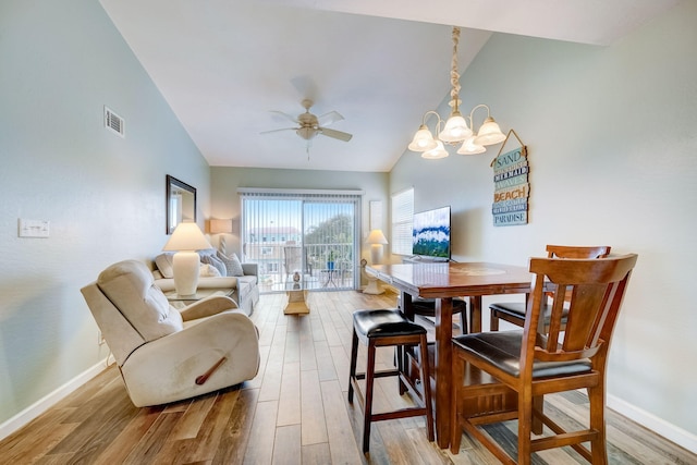 dining room featuring high vaulted ceiling, ceiling fan with notable chandelier, and light hardwood / wood-style floors