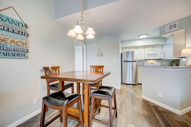 dining area with hardwood / wood-style flooring and a notable chandelier