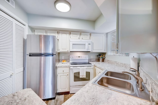 kitchen with sink, light hardwood / wood-style flooring, white appliances, and white cabinets