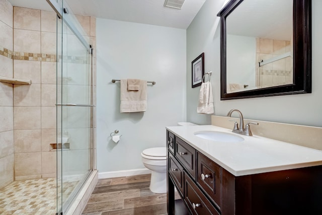 bathroom with a shower with shower door, vanity, wood-type flooring, and toilet