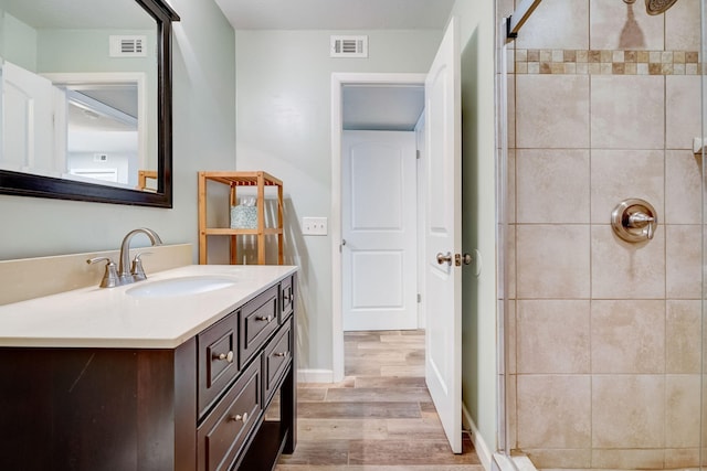 bathroom featuring tiled shower, wood-type flooring, and vanity