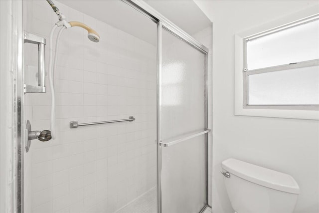 bathroom with a shower with door and toilet