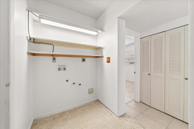 clothes washing area featuring hookup for an electric dryer, hookup for a washing machine, light tile floors, hookup for a gas dryer, and a textured ceiling