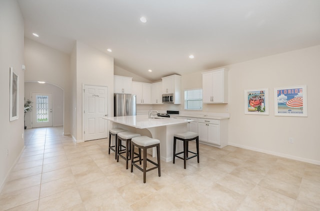 kitchen featuring sink, stainless steel appliances, a kitchen bar, a kitchen island with sink, and white cabinets