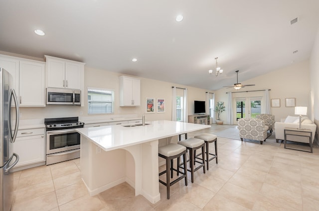 kitchen with stainless steel appliances, sink, white cabinetry, lofted ceiling, and an island with sink