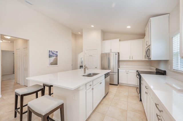 kitchen featuring appliances with stainless steel finishes, vaulted ceiling, a kitchen island with sink, sink, and white cabinets