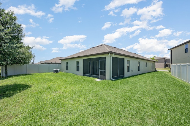 back of property with a lawn, a sunroom, and central air condition unit