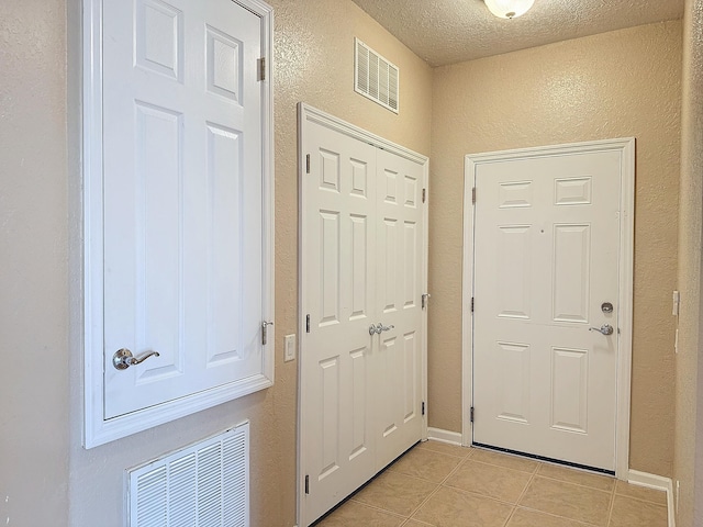 doorway to outside featuring light tile patterned flooring and a textured ceiling