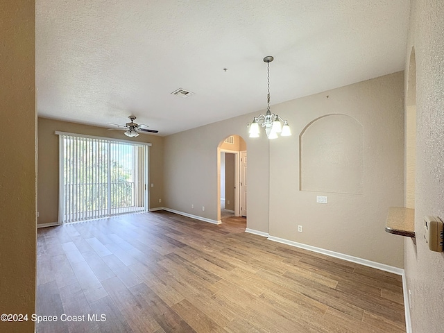 empty room featuring a textured ceiling, ceiling fan with notable chandelier, and light wood-type flooring