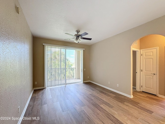 unfurnished room with ceiling fan, a textured ceiling, and light wood-type flooring