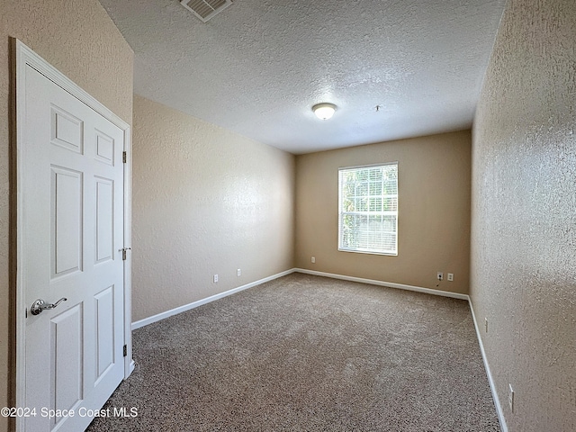 spare room featuring a textured ceiling and carpet floors