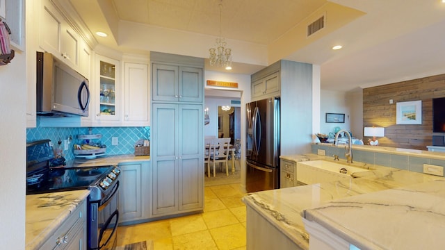 kitchen featuring stainless steel appliances, tasteful backsplash, light stone counters, sink, and pendant lighting