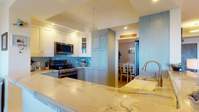 kitchen with sink, backsplash, decorative light fixtures, stainless steel appliances, and light stone countertops