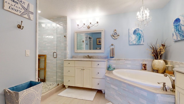 bathroom with a textured ceiling, hardwood / wood-style floors, large vanity, and plus walk in shower