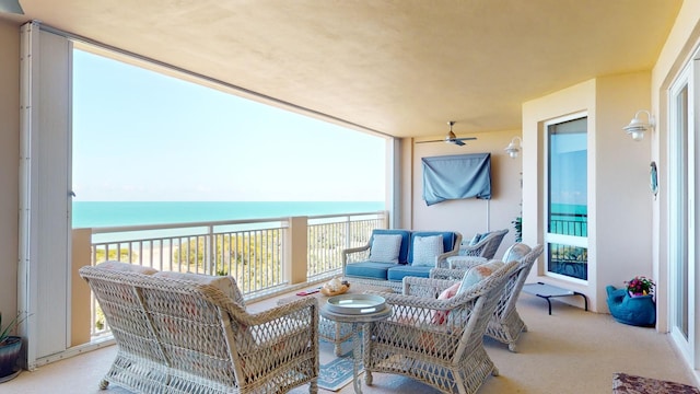 balcony featuring outdoor lounge area, ceiling fan, and a water view