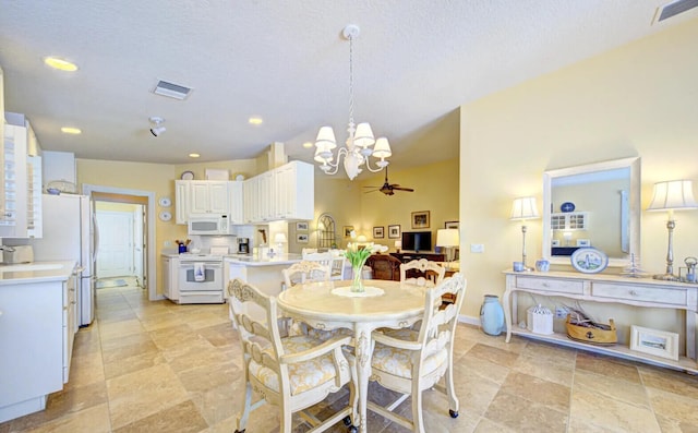 tiled dining area featuring ceiling fan with notable chandelier and a textured ceiling