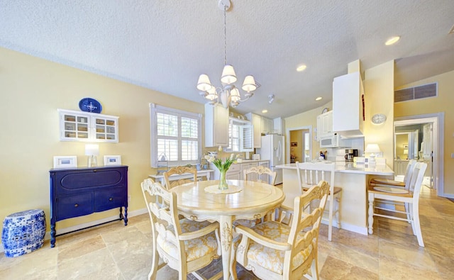 tiled dining area with lofted ceiling, an inviting chandelier, and a textured ceiling