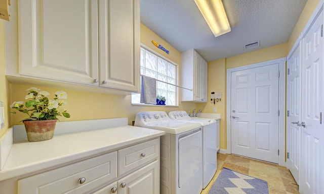 laundry area featuring a textured ceiling, cabinets, light tile floors, and washing machine and clothes dryer