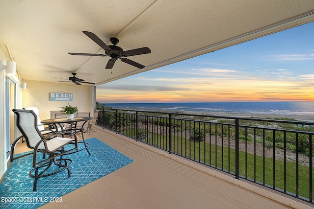 balcony at dusk with ceiling fan and a water view